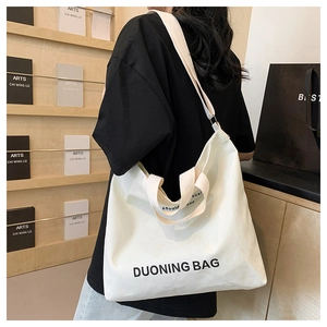 Detail of white canvas tote bag shoulder strap and printed lettering in a minimalist scene
