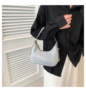 Close-up of a shimmering silver crescent underarm bag with gold metal hardware detailing