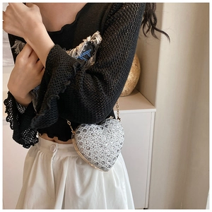 Detailed view of a sparkling silver heart-shaped sequin mini bag with a gold chain strap