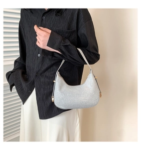 Detail of a sparkling silver crescent hobo bag with glitter texture and gold metal accents