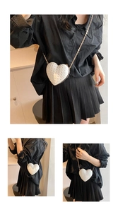 Detail view of heart-shaped white mini crossbody bag with gold chain and quilted texture
