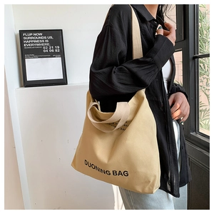 Detail view of khaki canvas tote bag with black lettering and dual handles