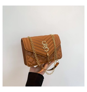 Detail der karamellbraunen Stepptasche mit goldener Kette und Fransenanhänger für Damen