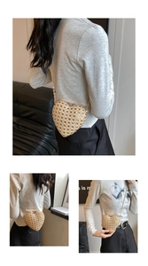 Detail of a beige heart-shaped woven crossbody bag with golden chain strap for women