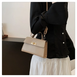 Detailed view of beige crossbody bag with golden rotary lock and adjustable shoulder strap