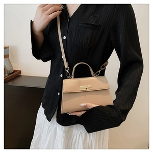 Beige mini crossbody handbag with gold twist lock shown on a model with classic style