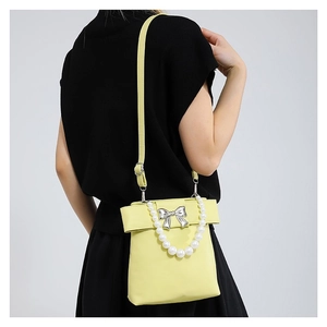Sac bandoulière jaune citron avec anse en perles et nœud argenté sur tenue noire