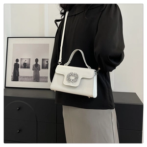 Détail d'un sac à main blanc carré avec boucle en strass brillante et bandoulière réglable