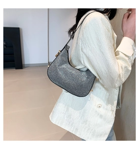 Detail of silver rhinestone hobo bag with sleek black shoulder strap on white blazer