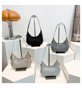 Close-up of sequined hobo bags in four metallic colors displayed on white pedestals