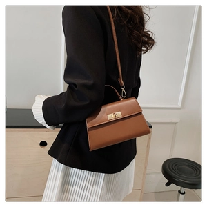 Brown trapezoid crossbody bag with gold twist lock shown from a side-rear angle on a model