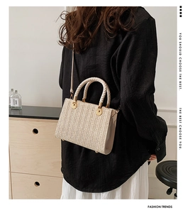 Detailed view of beige straw tote bag featuring woven texture and gold hardware details