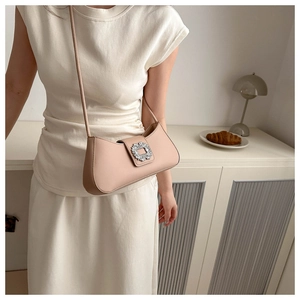 Detail of elegant beige baguette bag with sparkling crystal buckle and slim leather strap