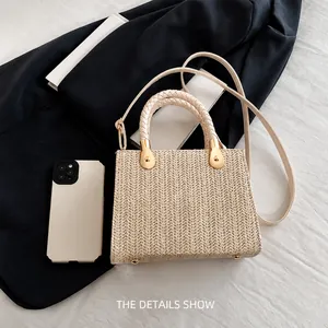 Detail view of beige woven tote bag with top handles and strap including phone size reference