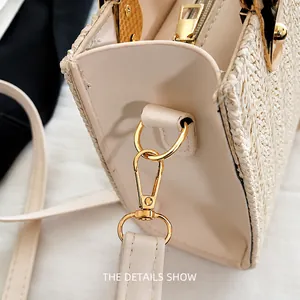Detail view of cream straw tote bag showing smooth leather trim and gold zipper hardware