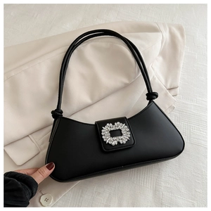 Detail of elegant black baguette bag featuring a crystal lock and knotted shoulder strap
