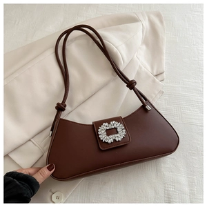Detail of dark brown leather underarm bag featuring a large sparkling rhinestone buckle