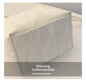 Detail shot of stitching craftsmanship and pleated texture on creamy white bucket bag