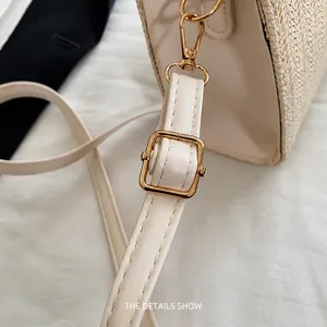 Detail of adjustable PU leather strap with gold buckle on woven beige straw tote bag