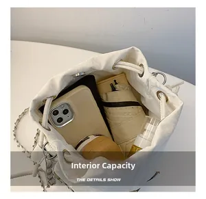 Internal capacity of the white canvas bucket bag showing phone, wallet, and umbrella