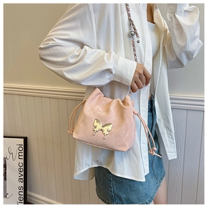 Detail of pink glossy drawstring bucket bag with silver butterfly and chain strap