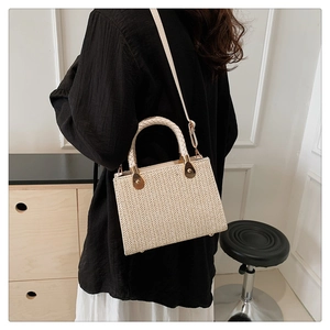 Detail of cream woven tote showing herringbone texture and gold metallic hardware