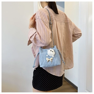 Detail of light blue drawstring bucket bag with silver butterfly and plush ball charms