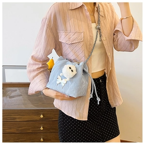 Detail of light blue drawstring bucket bag with silver chain strap and butterfly charm