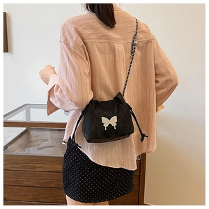 Detail of black drawstring bucket bag with white butterfly print and silver chain strap