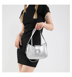 Detail of silver crossbody bag featuring a sparkling rhinestone buckle and metallic finish
