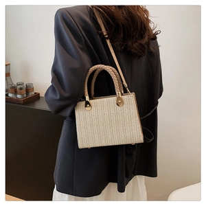 Elegant beige woven square handbag with circular handles and leather shoulder strap