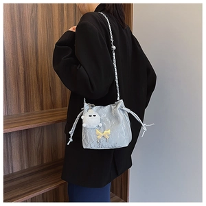 Detail of light blue bucket bag with gold butterfly accent and white pompom charm