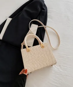 Detailed view of woven white handbag with round handles and gold metallic hardware accents