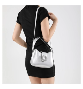 Detail of silver metallic shoulder bag featuring a sparkling rectangular rhinestone buckle