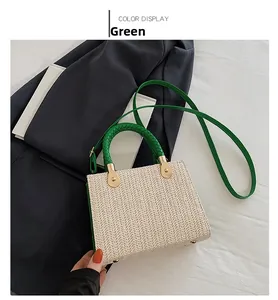Detail of woven straw handbag with green braided handles and golden metal protective feet