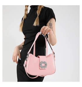 Detail of pink leather handbag featuring a luxury square rhinestone buckle on black dress