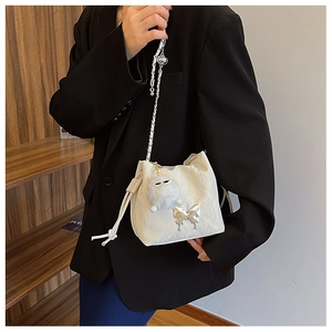 Elegant white drawstring bucket bag with silver butterfly pendant and chain strap
