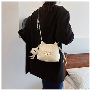 Quilted white shoulder bag with silver butterfly buckle and plush doll on black suit