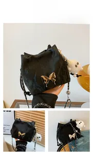 Detail of black bucket bag with metallic butterfly, pleated texture and furry charm