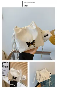 Detail of cream white bucket bag with black butterfly clasp and plush charm accessory