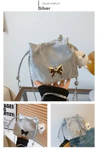 Silver drawstring bucket bag featuring butterfly buckle and white sheep plush keychain