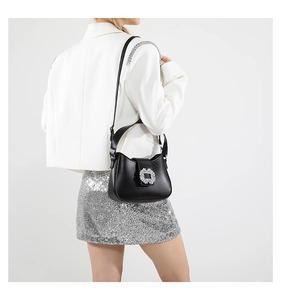 Side view of a black underarm bag with a crystal buckle worn over a sequin skirt