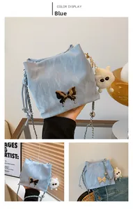 Detail of light blue bucket bag with metal butterfly ornament and plush charm