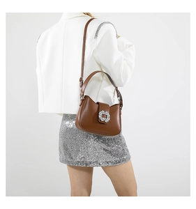 Detailed view of a brown leather shoulder bag with a sparkling rhinestone buckle decoration