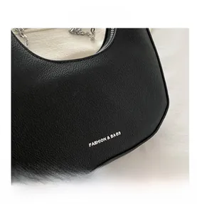 Macro shot of black lychee grain leather texture and silver zipper on a shoulder bag