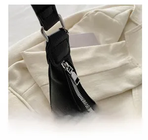 Close-up of smooth silver zipper and litchi texture leather on black underarm bag