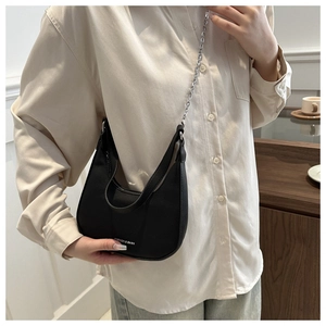 Detailed view of black crescent underarm bag with lychee texture and silver chain strap