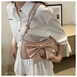 Detailed view of pink patent leather crescent bag with oversized decorative bow