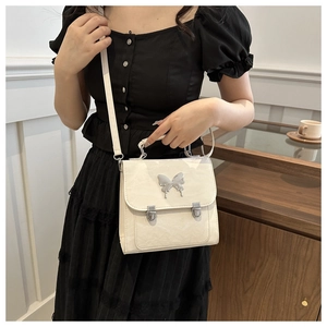 White mini shoulder bag with silver butterfly buckle and textured leather on a model