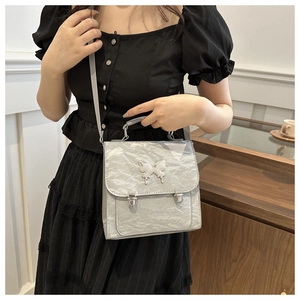 Detail of silver metallic textured crossbody bag with butterfly buckle and clasp
